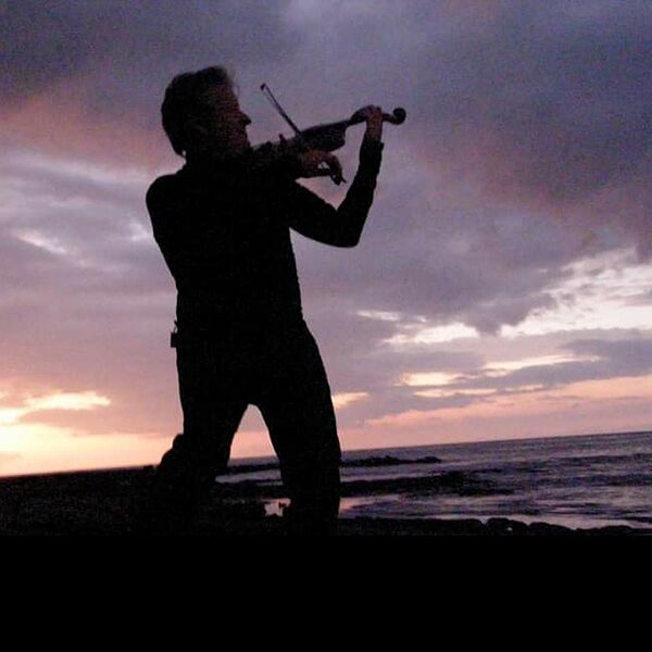 Chris Kranyak playing violin during a tropical sunset